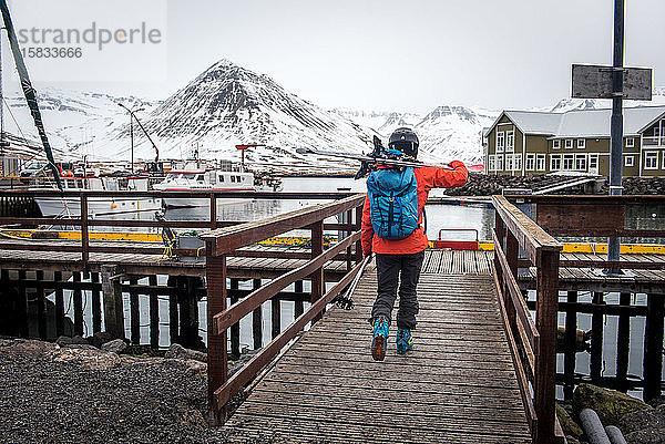 Eine Frau geht mit Skiern auf einen Dock in Island