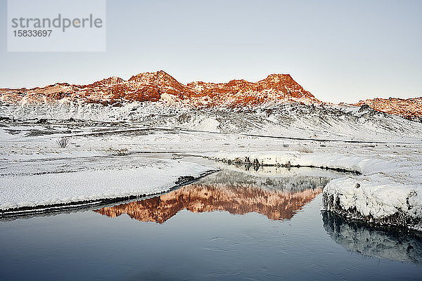 Winterfluss gegen Berge mit Schnee