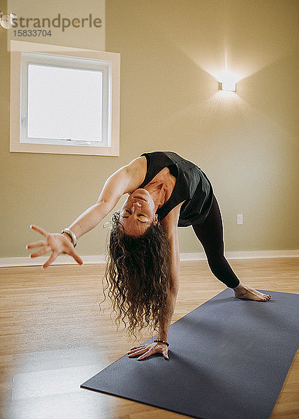 Weibliche Person mit geschlossenen eeditorischen Konzentraten beim Üben von Yoga in geschlossenen Räumen