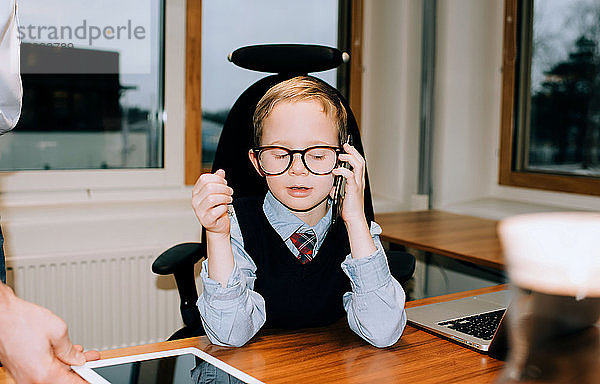 Junge am Telefon im Arbeitszimmer seines Vaters