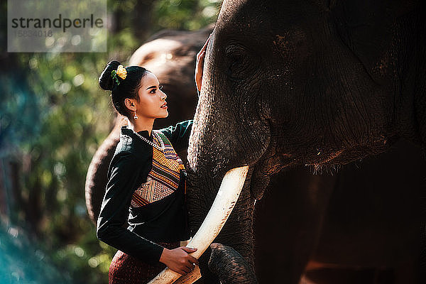 Thailand  Schöne Thailänderin und Elefant im Wald weari