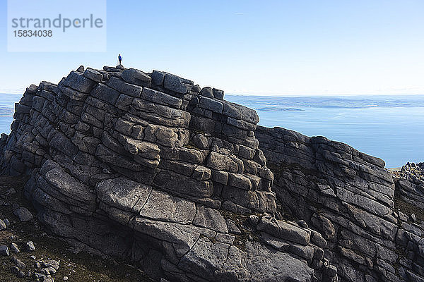 Silhouette einer Person auf gestapelten Felsen über dem Meer