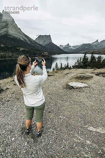 Frau fotografiert mit dem Handy die Aussicht auf die Berge  Montana