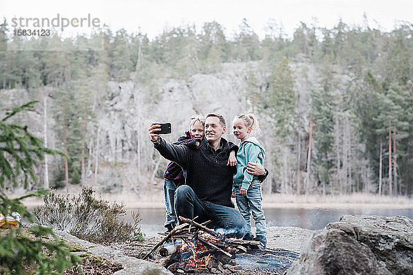 Vater fotografiert mit seinen Kindern am Lagerfeuer