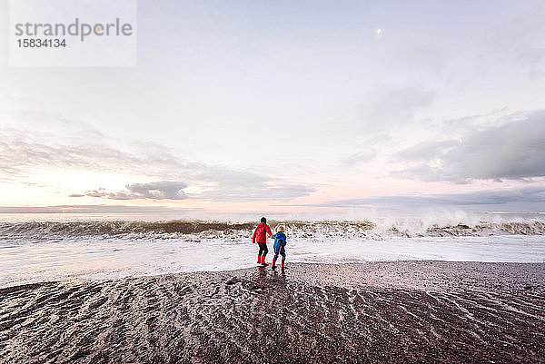 Zwei Jungen spielen gemeinsam draußen an der neuseeländischen Küste