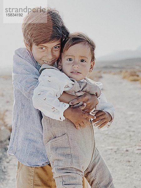 Porträt von zwei Kindern  die sich in der Wüste umarmen