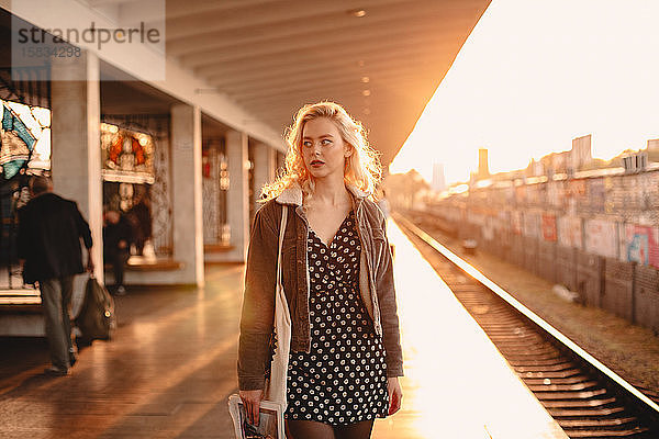 Junge Frau wartet bei Sonnenuntergang am U-Bahnhof auf den Zug
