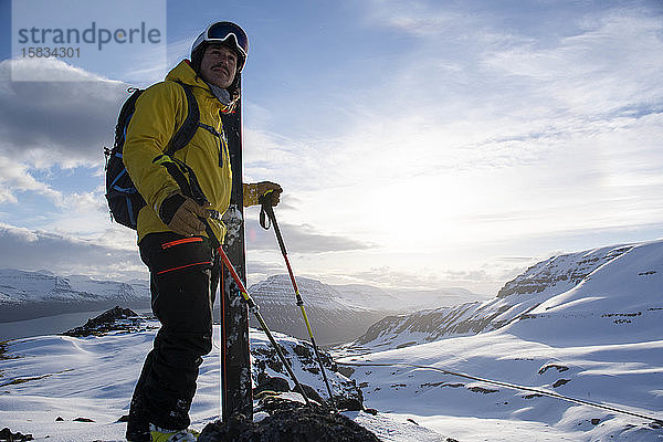 Porträt eines männlichen Skifahrers mit Blick auf die Sonnenuntergangsansichten von Island