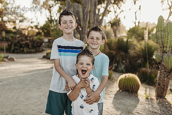 Porträt von drei jungen Geschwistern lächelnd im sonnigen Kaktusgarten