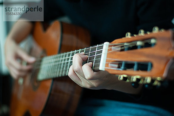 Frauenhände beim Spielen der akustischen Gitarre  Nahaufnahme