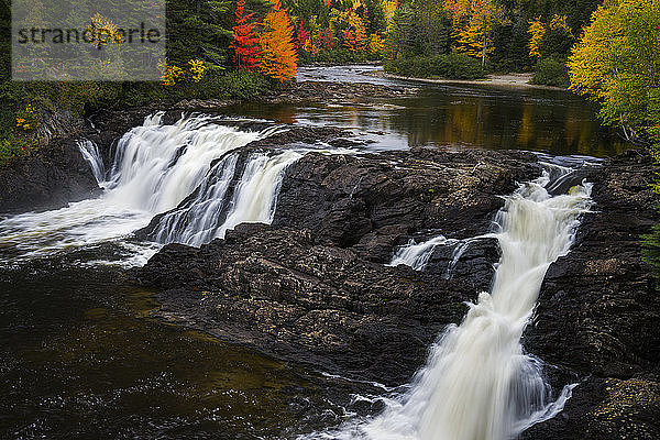 Herbstfarben und zwei Wasserfälle an einem Fluss in Maine