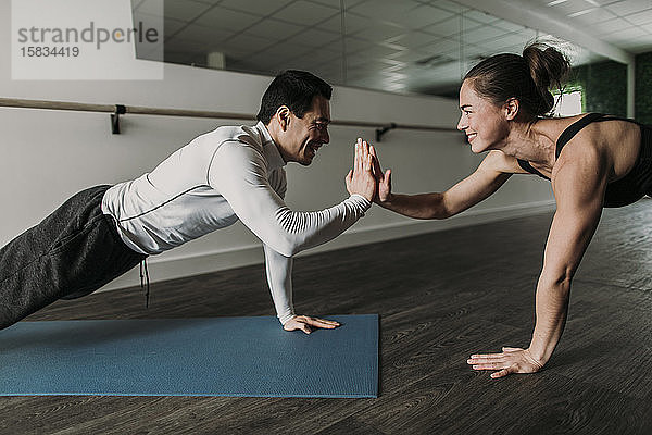 männliche und weibliche Freunde High Five beim Liegestützen im Fitnessstudio