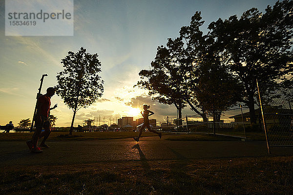 Die Silhouette einer Frau  die bei Sonnenuntergang in Boston läuft.