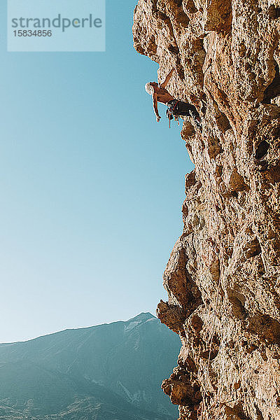 Rückansicht eines männlichen Kletterers an der Wand mit El Teide im Rücken