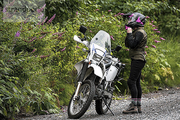 Eine Frau macht eine Pause vom Motorradfahren und nimmt ihren Helm ab.