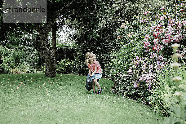 junges Mädchen gießt ihren Garten auf dem Land in England mit einer Gießkanne
