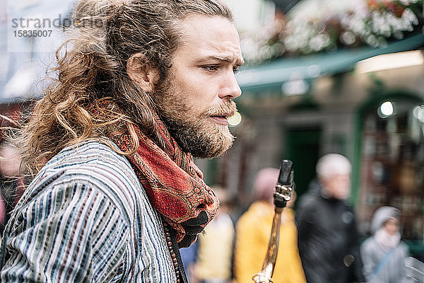 Blonder Mann mit langen Haaren und Bart in Hippie-Kleidung mit Saxophon