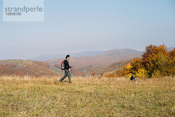 Mann mit Hund beim Wandern in den Herbstbergen