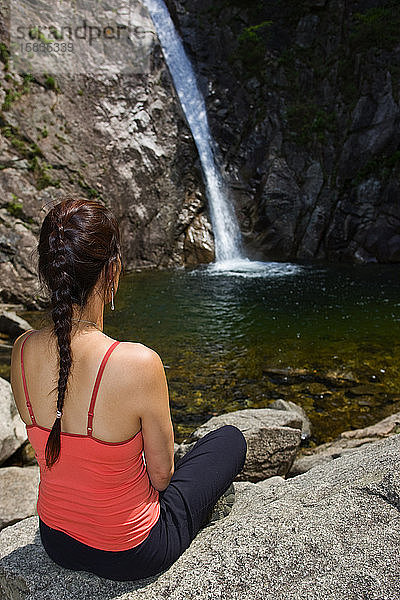 Frau sitzt an einem Wasserfall im Seroksan-Nationalpark