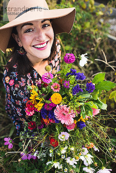 glücklich lächelnde Frau in einem Garten mit frischen Blumen