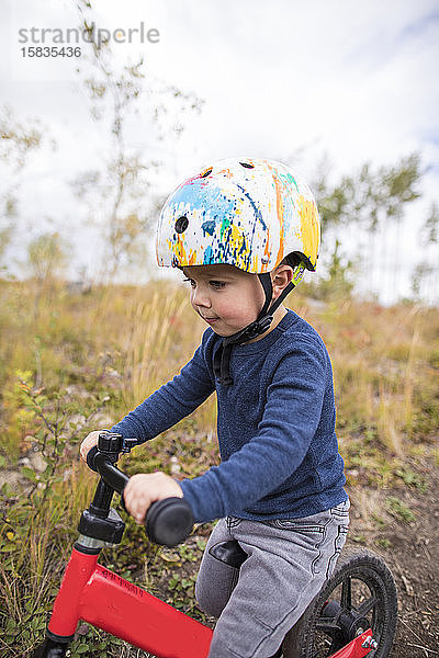 Seitenansicht eines Jungen auf einem roten Fahrrad.