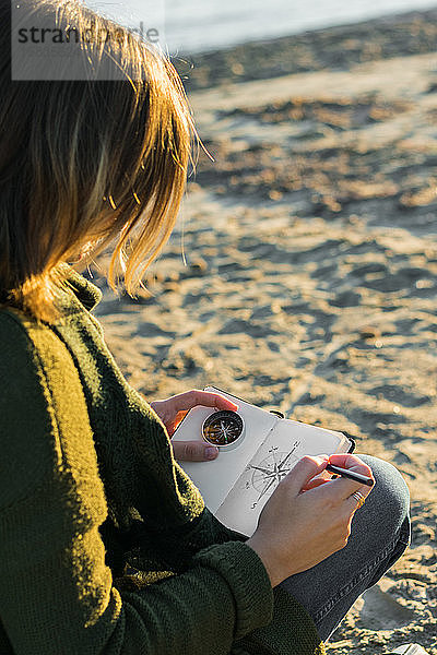 Junge Frau zeichnet einen Kompass in einem Notizbuch. Lebensstil  Reisen