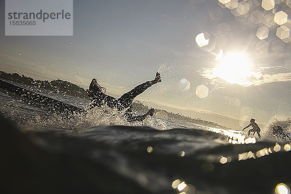 Silhouette der Surfer bei Sonnenuntergang