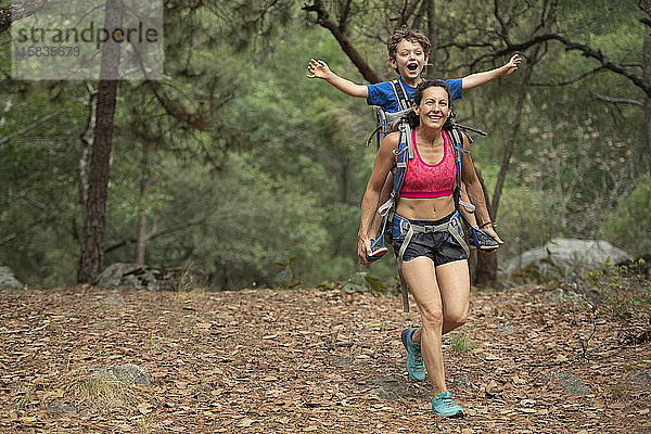 Mutter rennt mit ihrem Kleinkind im Rucksack auf einem Wald in Huasca de Ocampo  Mexiko