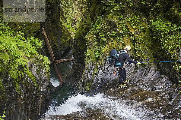 Mann  der sich neben einem Wasserfall im Frost Creek Canyon abseilt.