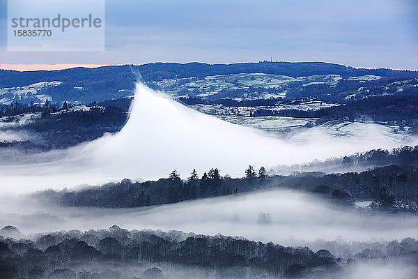 Blick hinunter in das Langdale-Tal oberhalb des durch eine Temperaturinversion gebildeten Talnebels auf Loughrigg  nahe Ambleside im Lake District National Park. Die örtliche Erwärmung hat diese ve