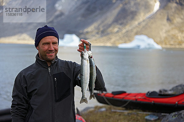 Mann hält frischen Seesaibling in Grönland