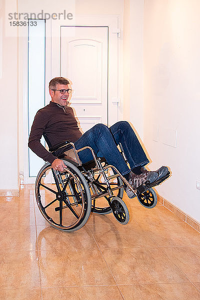 Ein Mann spielt mit einem Rollstuhl Balancieren und hat Spaß