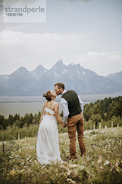 Braut und Bräutigam küssen sich in der Natur vor den Bergen  Wyoming