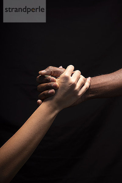 Männer- und Frauenhände mit unterschiedlichen Hauttönen halten sich gegenseitig