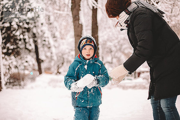 Mutter und Sohn spielen im Winter mit Schnee