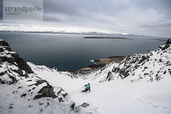 Eine Frau  die in Island Skilanglauf bis zum Meer betreibt.