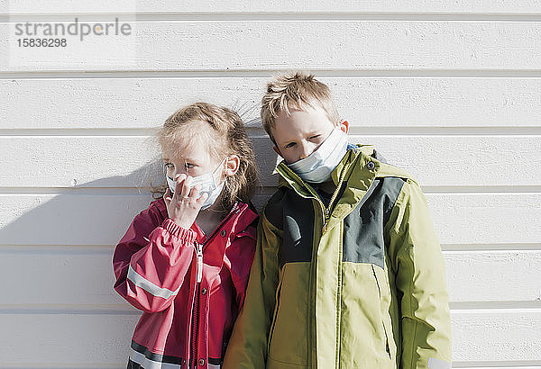 Geschwister tragen medizinische Masken zum Schutz vor dem Coronavirus