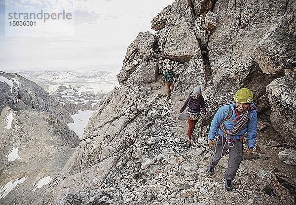 Drei Bergsteiger wandern entlang einer Klippe in den Tetons of Wyoming