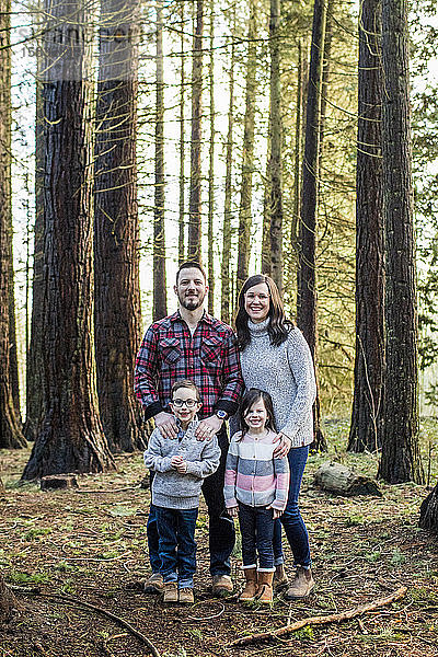 Porträt einer attraktiven Familie  die im Wald steht.