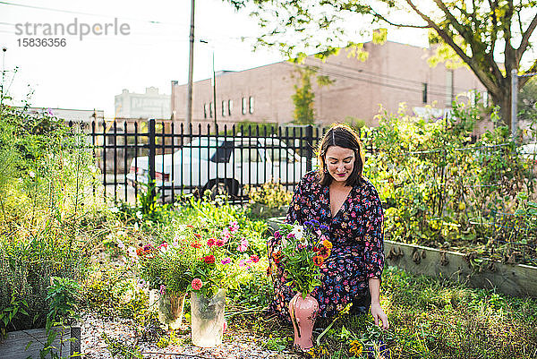 glückliche Frau pflückt Blumen im Stadtgarten