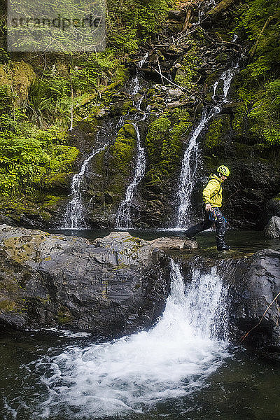 Mann geht beim Canyoning über einen kleinen Wasserfall.