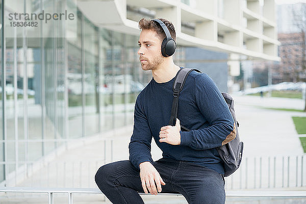 Junger Mann mit Kopfhörern auf der Straße in der Stadt