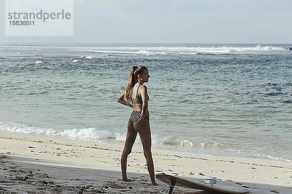 Junge Frau mit Surfbrett am Strand