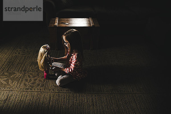 Kleines Mädchen spielt mit Puppe im Wohnzimmer