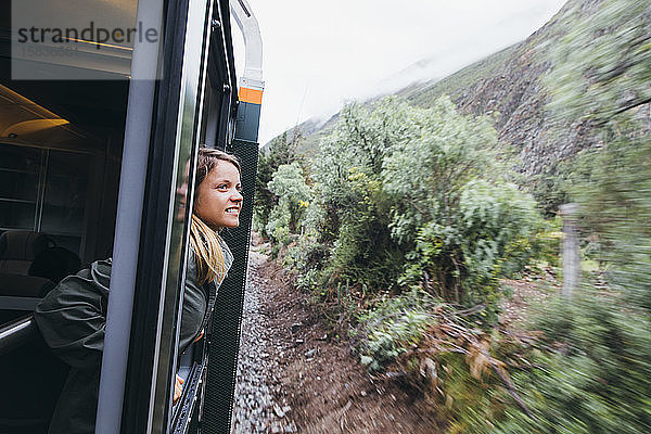 Eine junge Frau schaut aus einem Fenster auf dem Weg nach Machu Picchu