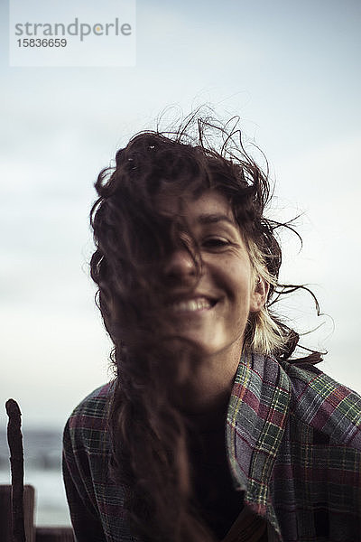 Wildes Haar natürliches Mädchen lächelt und lacht vor der Kamera am abgelegenen Strand