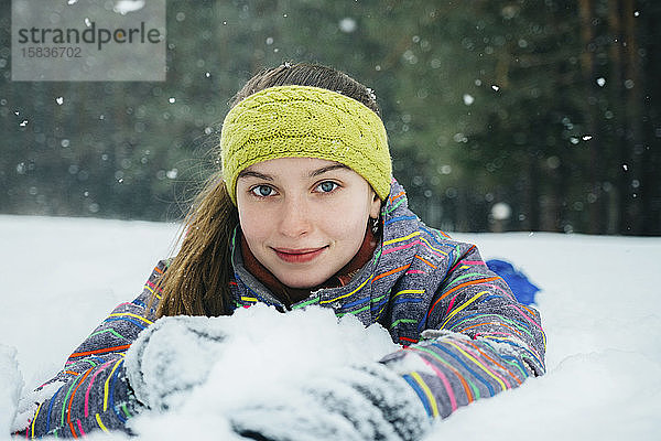 das Mädchen liegt im Schnee und lächelt