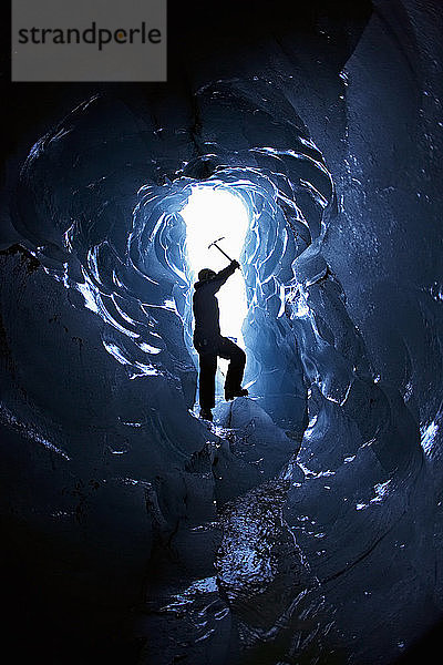 Silhouette eines reifen Mannes am Eingang einer kleinen Eishöhle