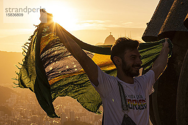 Schöne Szene eines Touristen auf dem Zuckerhut mit der brasilianischen Flagge