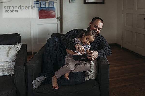 Vater und kleine Tochter spielen während der Isolation auf dem Tablett